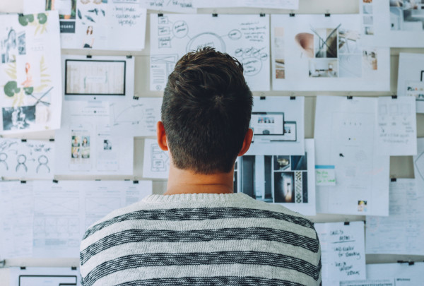 Canva - Man Wearing Black and White Stripe Shirt Looking at White Printer Papers on the Wall.jpg